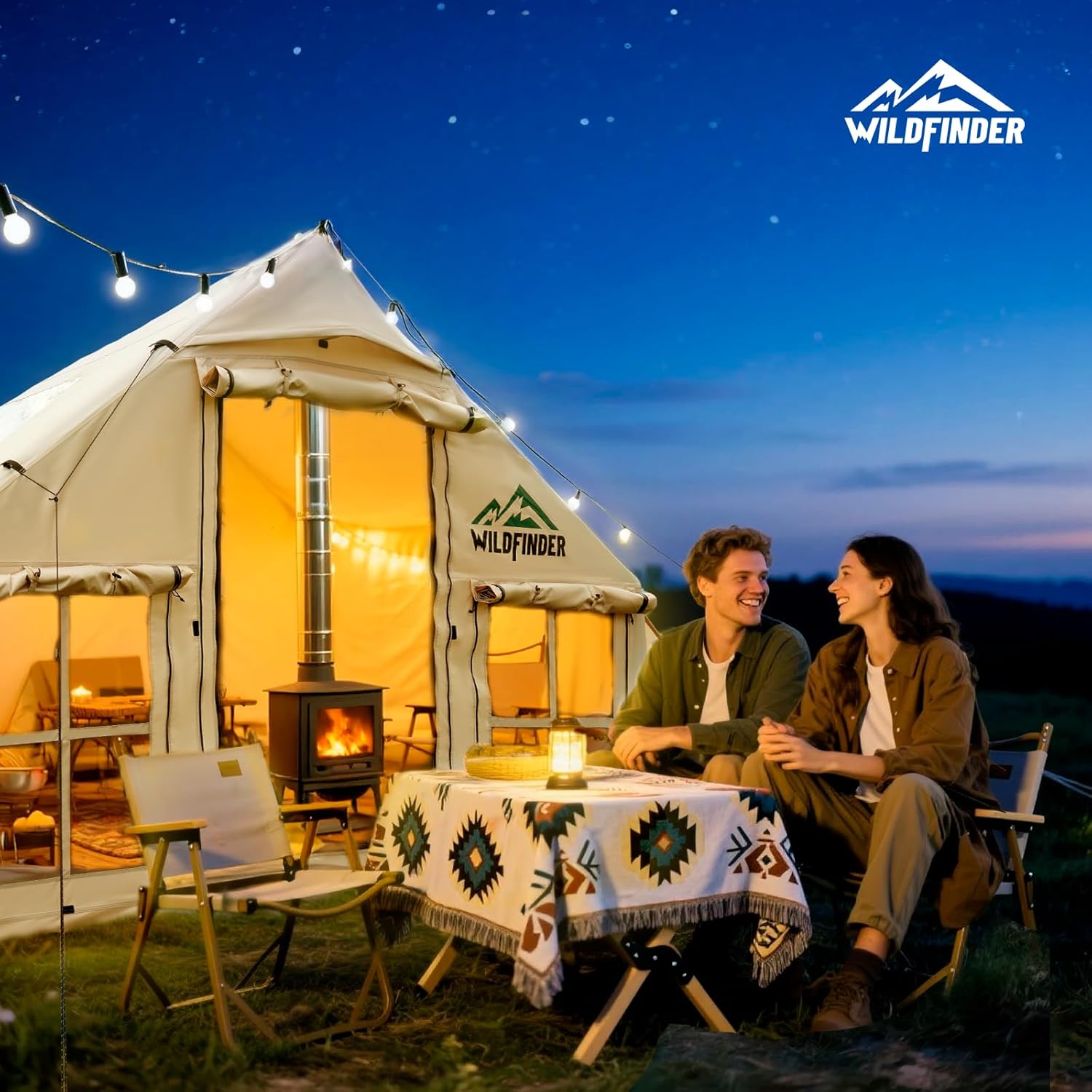WildFinder off white inflatable hot tent lit up at night with a couple by a stove